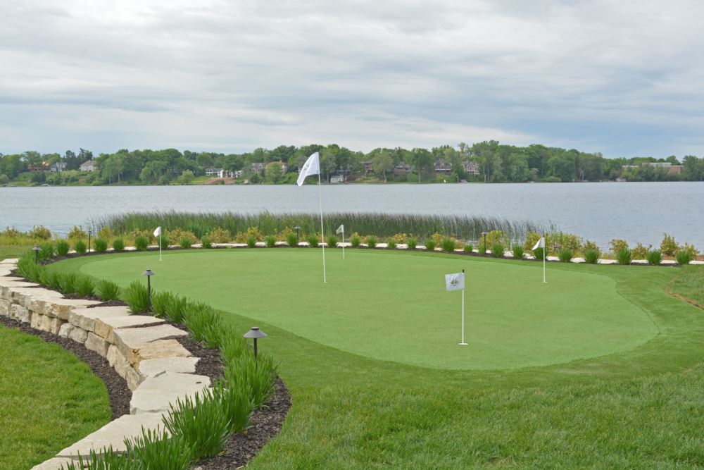 artificial turf putting green with a lake of water behind it