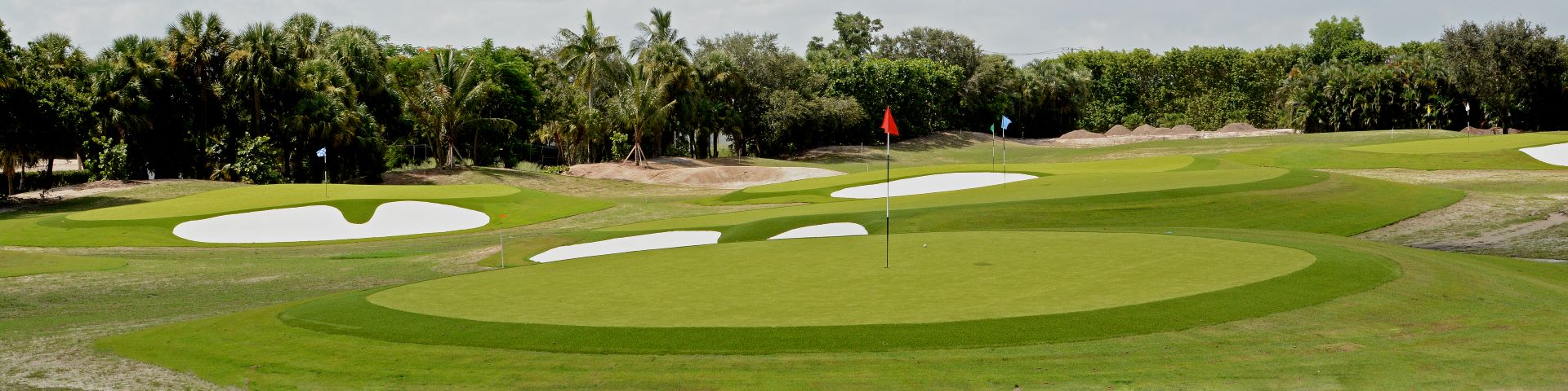 Multi-hole artificial turf putting course with sand bunkers and colored flagsticks at a South Florida golf facility