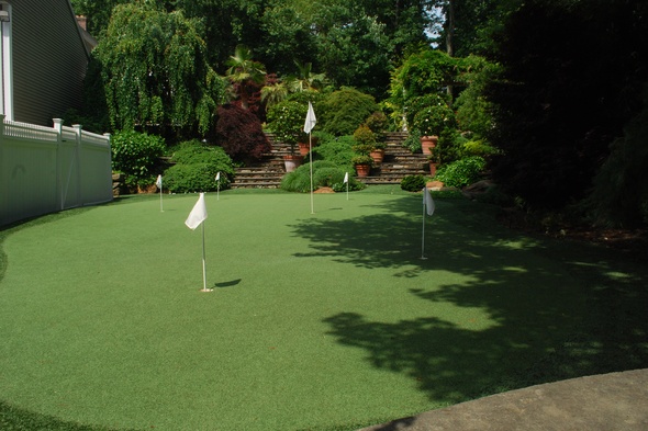 Phoenix Synthetic grass golf green with flags in a landscaped backyard