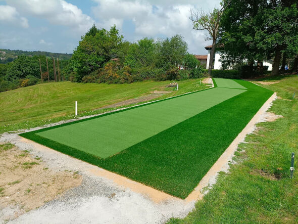 Phoenix Outdoor tee line consisting of one continuous green synthetic grass strip surrounded by trees