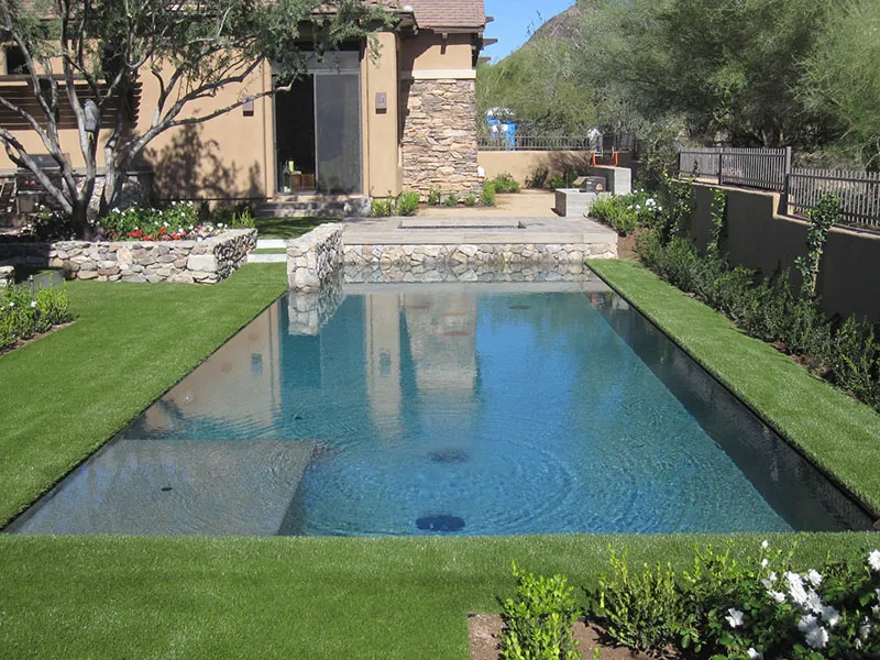 artificial turf in a front yard with a pool and house