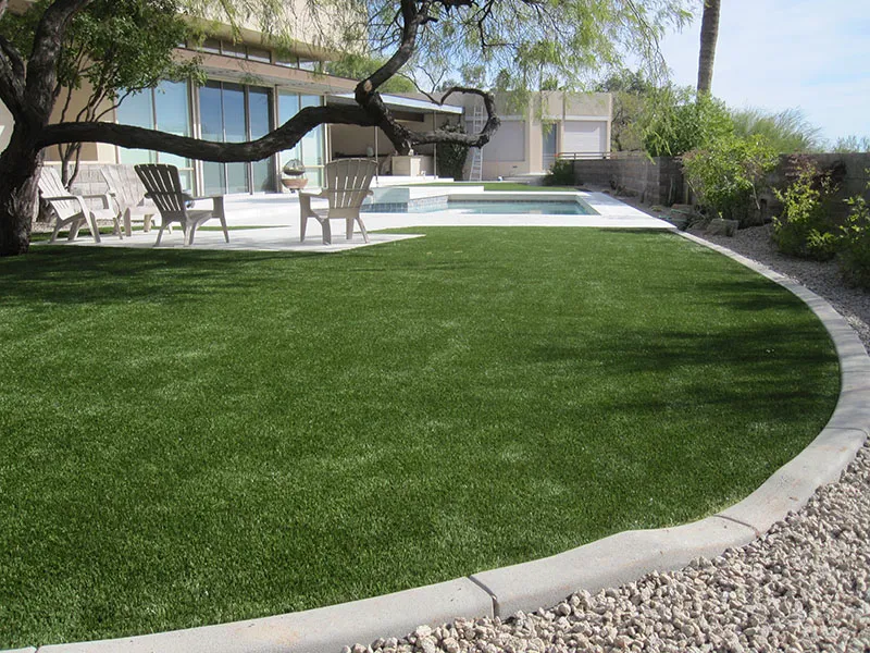 artificial turf in a front yard with a house and a pool