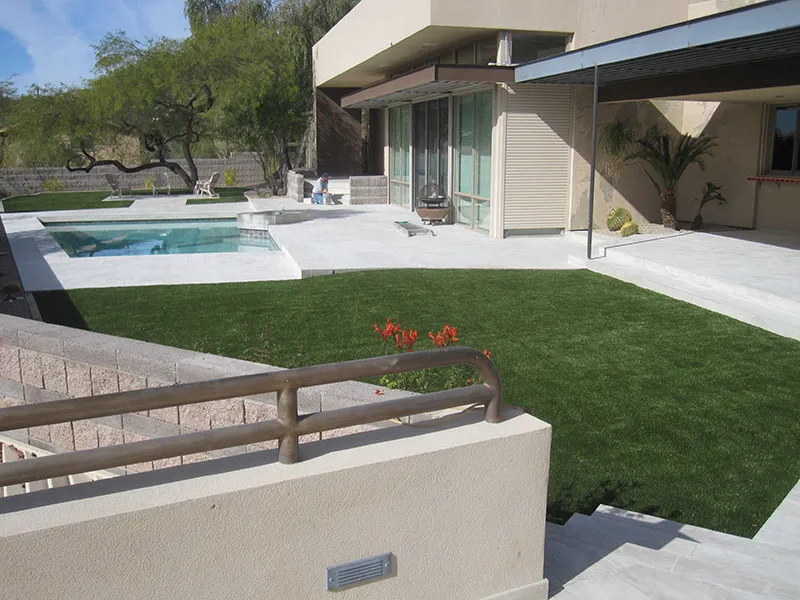 artificial turf in a front yard with a house and a pool