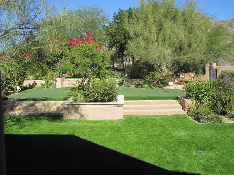 a putting green in a backyard surrounded by flowers