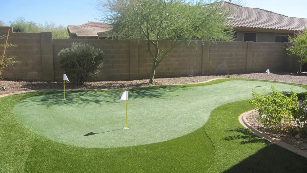 a putting green in a backyard next to a fence