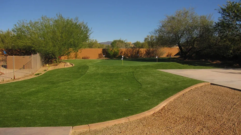 a putting green in a backyard in a fenced in area