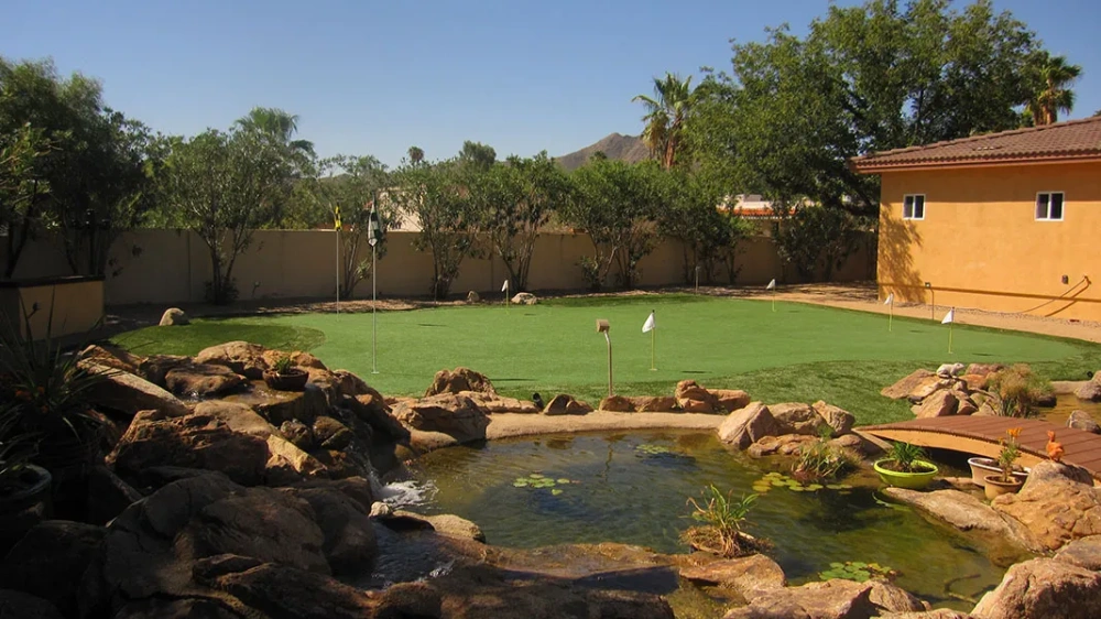 a putting green in a backyard with a house in the background