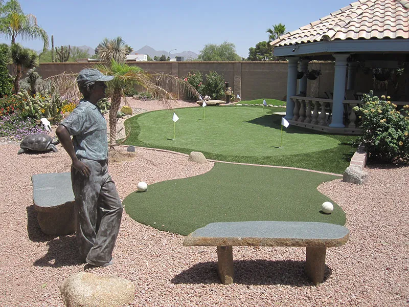 a putting green in a backyard with a statue and gazebo