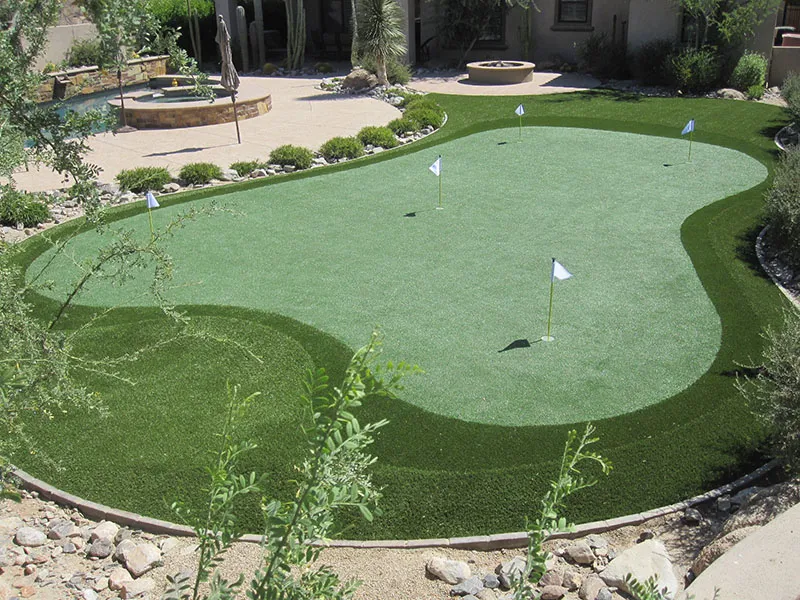 a putting green in a backyard with a view of the house