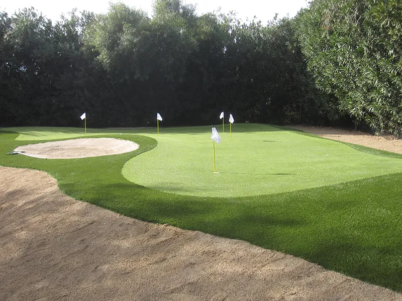 a putting green and sand bunker with hole flags